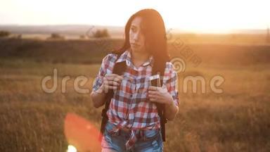 嬉皮<strong>青年</strong>女孩步行与背包智能手机享受<strong>日</strong>落在高峰后方。 背景视图下的游客
